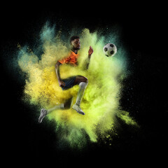 Wall Mural - Young African sportsman soccer football player in explosion of yellow neon powder isolated on dark background