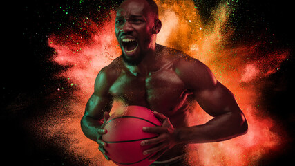 Wall Mural - One young African sportsman basketball player in explosion of colored neon powder isolated on black background