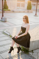 Poster - Vertical shot of a Caucasian female with black dress sitting outdoors