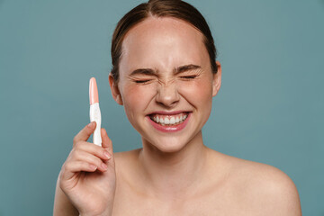 Half-naked ginger woman smiling and showing pregnancy test