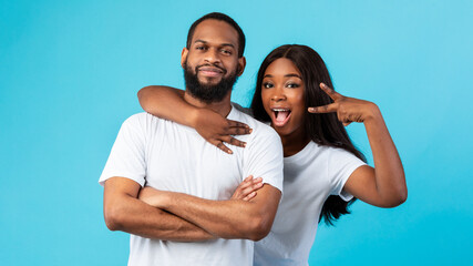 Wall Mural - Black couple posing showing victory sign or peace gesture