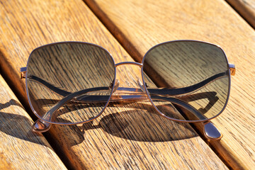 Metal thin trendy sunglasses on wooden table