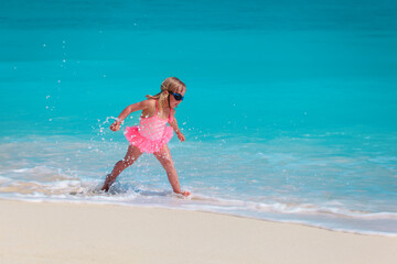 Wall Mural - happy little girl play with water on beach, family vacation