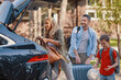© gstockstudio - Happy young family packing stuff into the car and smiling while standing near house