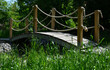 arched wooden bridge in the park. the railing posts are connected by a strong jute rope. Knots finished with a rope work of a Japanese garden.