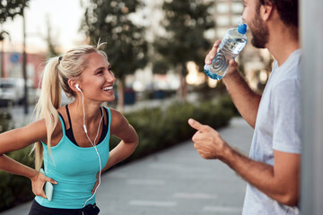 Wall Mural - Two sporty young people making pause after jogging and exercising in urban area.