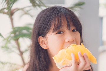 7 years old asian kid girl eat fresh fruit.Little asian thai girl eating durian fruit at home delicious.She make every happy and yummy face.Sweet and creamy durian.Durians are the king of fruits.