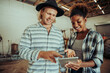 © Prins Productions - Mixed race couple working on farm project standing in barn typing on digital tablet