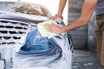 a man with a rag wipes the foam on the car