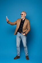 Full Length Of Happy Middle Aged Man In Sunglasses Taking Selfie On Cellphone On Blue