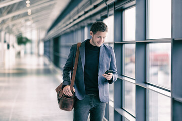 mobile phone business man walking in airport with messenger bag using cellphone texting sms message 