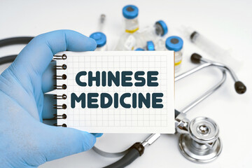 There is a stethoscope on the table, the doctor holds a notebook in his hand with the inscription - CHINESE MEDICINE