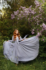  Girl in long dress near lilac on green summer background