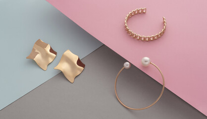 Wall Mural - Modern design gold bracelets and wavy shape earrings pair on pastel colors paper