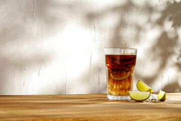 Poster - A cold fresh drink on a summer day on a wooden table in the shade of the interior and the shadows of trees on a rustic textured wall 