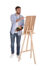 Poster - Man painting with brush on easel against white background. Young artist