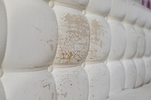 Close Up Of Damaged White Leather Soft Tufted Furniture Or Bed Panel Upholstery. Bad Quality Leather 