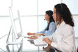 © sittinan - woman agent with headsets working in a call centre,Call center agent with headset working on support hotline in modern office. Call center worker accompanied by her team.