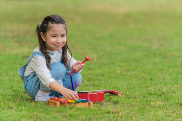 mixed race little girl have fun playing musical toy on grass lawn in park