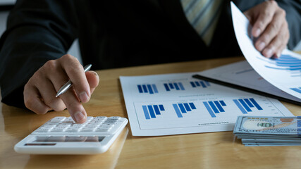 Business people doing business in finance and calculating, analyzing, graphing on costs of investments, real estate and more, tax system on the desk with laptops and calculators with documents