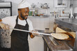 © prostooleh - African merican man baking pizza at commercial kitchen