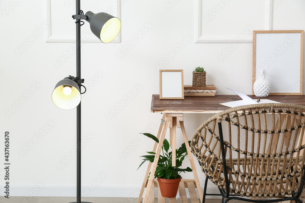 Modern workplace and lamp near light wall in room