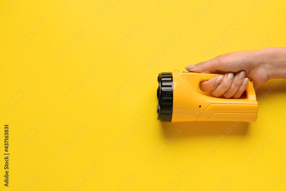 Female hand with modern flashlight on color background