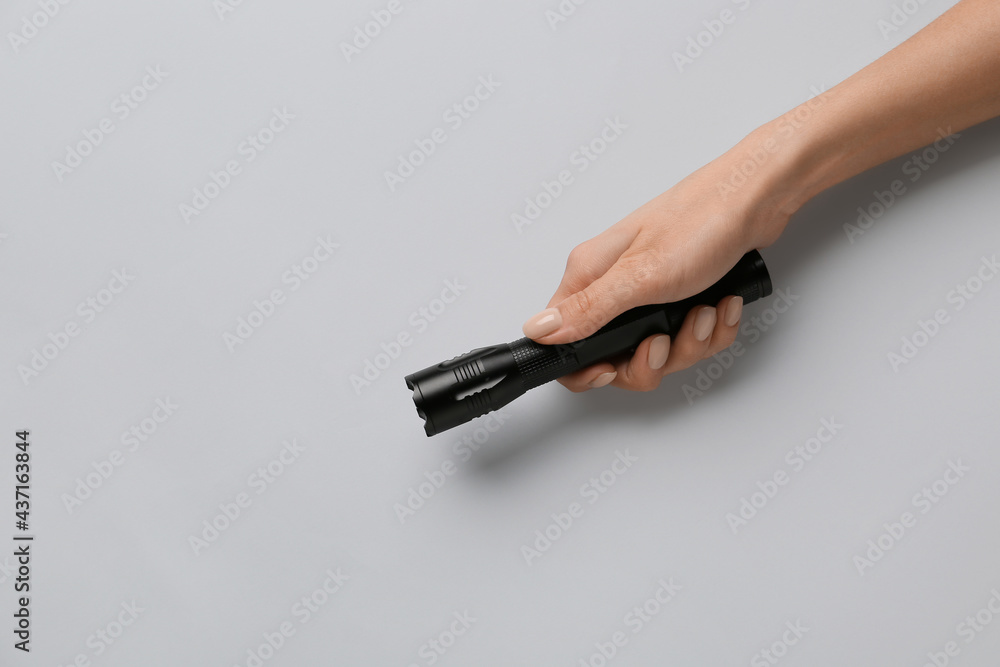 Female hand with modern flashlight on light background