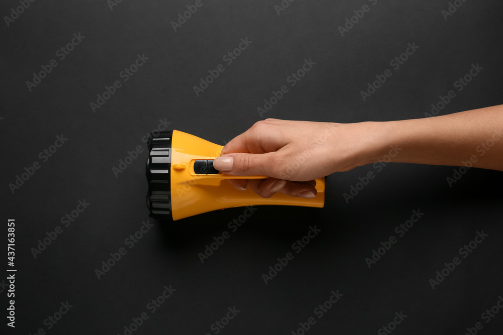 Female hand with modern flashlight on dark background