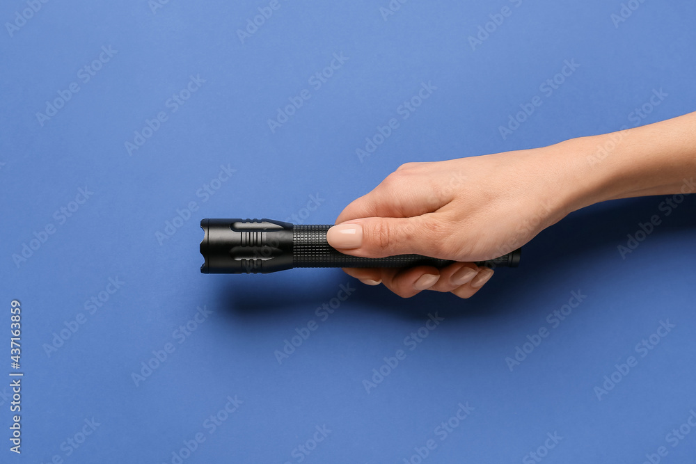 Female hand with modern flashlight on color background