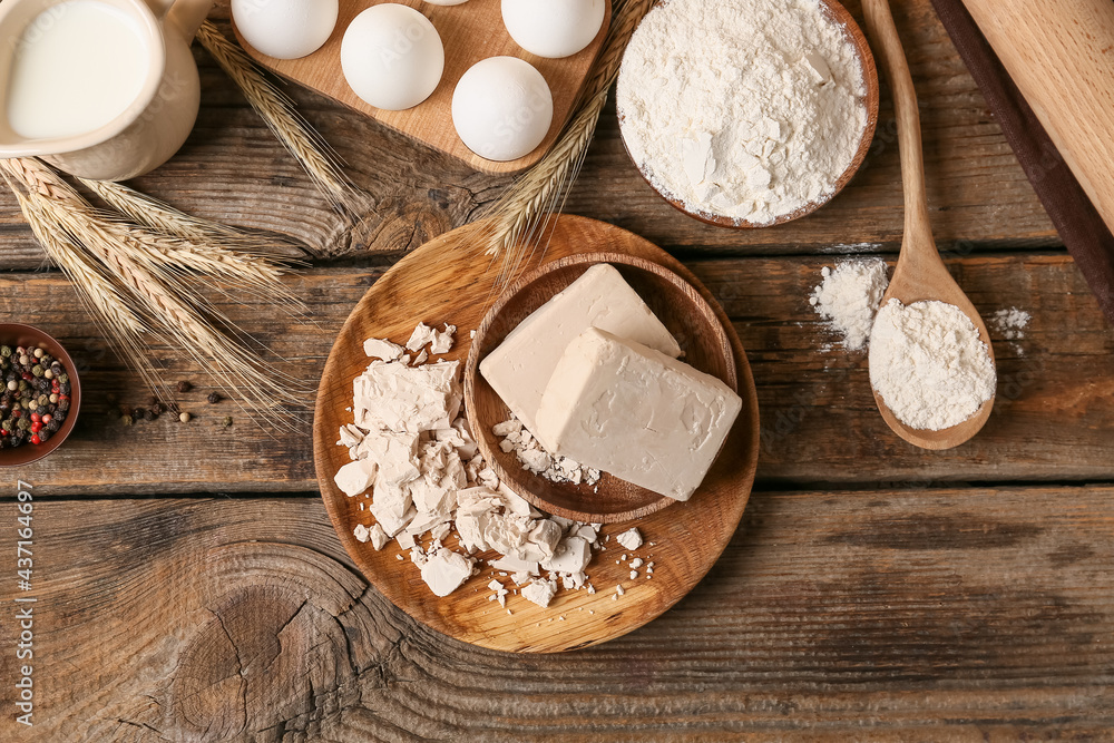 Plate with fresh yeast on wooden background