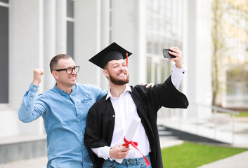 Wall Mural - Happy young man with his father taking selfie on graduation day