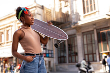 Portrait Of Happy African-american Woman With Skateboard. Young Stylish Woman With Skateboard Outdoors..