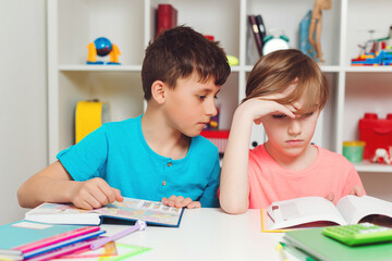 Tired schoolchildren are reading book at school. Sad school boys learning lessons. Education and school concept.