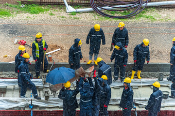 Tel Aviv, Israel - May 20 2021: Construction Workers working in the rain. Light rail tracks. blue collar worker. Concept Collaboration teamwork. Trucks, concrete mixer, bulldozer. High quality photo