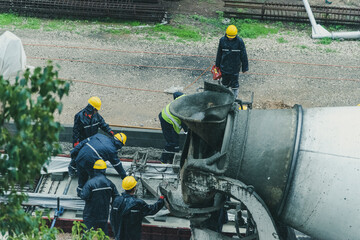 Tel Aviv, Israel - May 20 2021: Construction Workers working in the rain. Light rail tracks. blue collar worker. Concept Collaboration teamwork. Trucks, concrete mixer, bulldozer. High quality photo