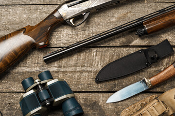 Wall Mural - Hunting equipment on old wooden background including rifle, knife, binoculars and cartridges