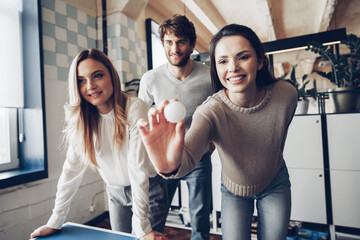 Young people coworkers playing beer pong in modern office