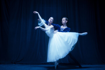 Young woman in wedding dress and man, two ballet dancers in art performance dancing isolated over dark background.