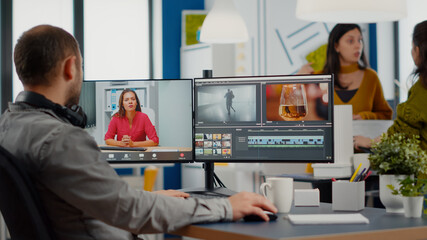 Poster - Videographer in web online conference with project manager on video call editing client work, getting feedback on commercial movie using post production software on two monitors in start up office