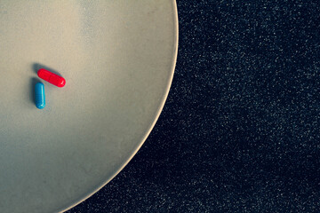 Wall Mural - Colored pills on a plate. Free space to write. Concept of replacing food with medication. Black background.