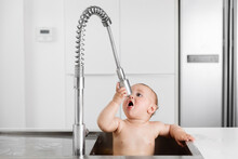Funny Baby Sitting In Kitchen Sink Drinking Out Of Faucet