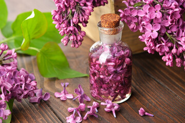 Wall Mural - Lilac essential oil or infusion bottle. Blossom lilac drink or extract. Syringa flowers on background.