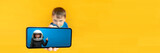 Fototapeta Panele - The child holds the phone in his hand for advertising on a yellow background. Color