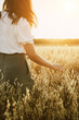 Young woman in a oats field. Girl walking through field and touches cereal. Rich Harvest concept. Banner with copy space.