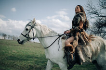 Woman Rides On Horseback In Field In Image Of Warrior Amazon.