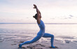 Caucasian flexible woman feeling balance and harmony during yoga practice doing Crescent pose during workout near sea, active female yogi enjoying vitality keeping figure and mental health