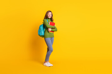 Sticker - Full length body size photo girl keeping book pile wearing backpack smiling isolated vivid yellow color background