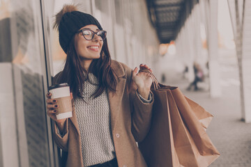 Wall Mural - Beautiful fashionable woman drink coffee walking near mall with shopping bags.