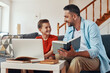 © gstockstudio - Happy young father helping his son with homework while homeschooling in the living room